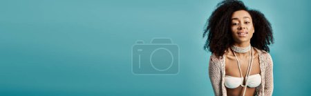 Photo for African American woman striking pose in trendy swimsuit against blue background. - Royalty Free Image