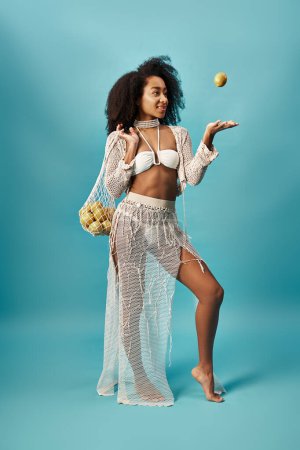 Foto de Hermosa mujer afroamericana se ve elegante posando con una fruta en la mano. - Imagen libre de derechos