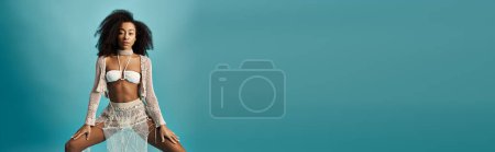 Téléchargez les photos : Jeune femme afro-américaine frappant une pose élégante sur un fond bleu vif. - en image libre de droit