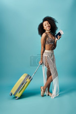 Une jeune femme afro-américaine élégante en bikini tenant une valise.
