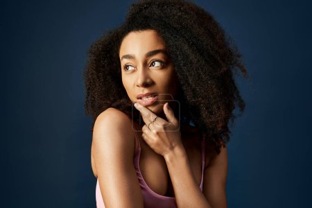 Photo for Woman with curly hairdo striking a thoughtful pose with hand on chin. - Royalty Free Image