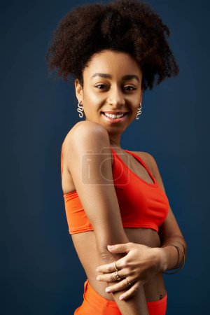 Foto de Elegante mujer afroamericana posando con confianza en un top naranja. - Imagen libre de derechos
