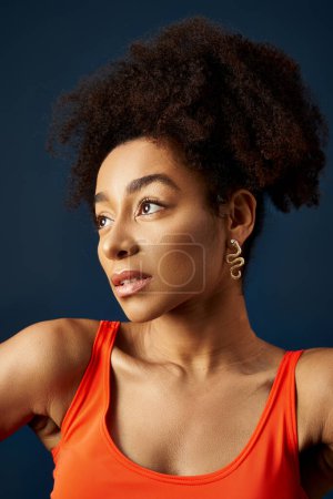 Téléchargez les photos : Jeune femme afro-américaine élégante avec une coiffure bouclée frappant une pose. - en image libre de droit