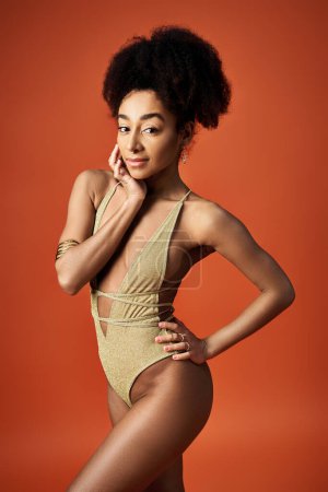 Photo for Young African American woman in gold swimsuit posing elegantly. - Royalty Free Image