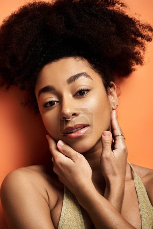 Téléchargez les photos : Jeune femme afro-américaine élégante, avec une coiffure bouclée, frappant une pose. - en image libre de droit