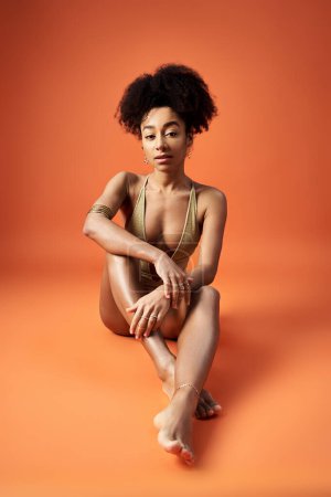 Photo for African American woman in stylish bikini, striking a pose on vibrant orange backdrop. - Royalty Free Image