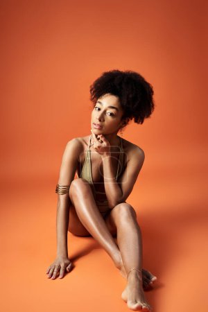 Foto de Stylish African American woman posing in a trendy bikini on an orange background. - Imagen libre de derechos