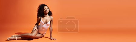 Téléchargez les photos : Femme afro-américaine en maillot de bain tendance relaxant sur fond orange. - en image libre de droit