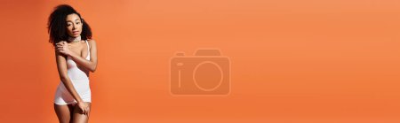 Téléchargez les photos : Jeune femme afro-américaine pose dans des maillots de bain à la mode sur fond orange. - en image libre de droit