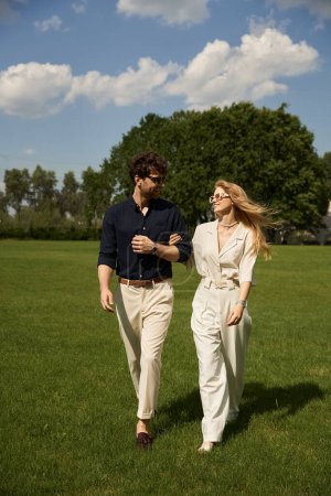 A graceful couple leisurely walks through a lush, grassy field, embodying a sense of peace and connection with nature.