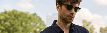 Photo for A man in sunglasses marks his presence in a verdant field, exuding an air of mystery and style. - Royalty Free Image