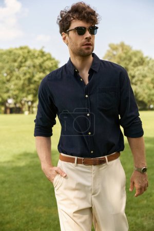 Ein stilvoller Mann in marineblauem Hemd und brauner Hose sieht in einem Outdoor-Umfeld schneidig aus.