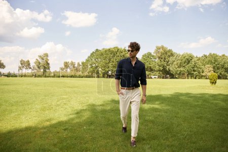 Foto de Un hombre pasea por un exuberante campo de hierba bajo un cielo despejado, empapado en la paz y la tranquilidad de la naturaleza. - Imagen libre de derechos