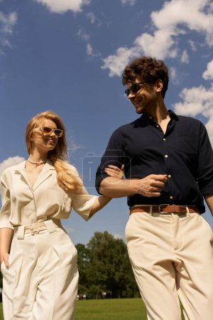 Elegante pareja con viejo estilo de dinero disfrutando de un tranquilo paseo por un vasto campo verde bajo el cielo.