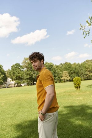 Foto de Un hombre con una camisa amarilla se levanta con gracia en un exuberante campo de hierba. - Imagen libre de derechos