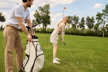 Ein junges Paar in eleganter Kleidung spielt zusammen Golf auf einer grünen Wiese in einem Luxus-Golfclub mit einer Golftasche in der Nähe.