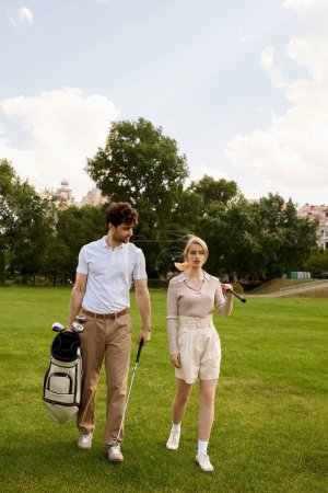 A stylish couple in elegant attire walking together on a lush green golf course under the open sky.