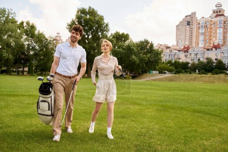 Foto de Una pareja elegante pasea tranquilamente por un lujoso campo de golf, rodeado de la vegetación del paisaje sereno. - Imagen libre de derechos