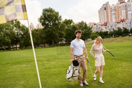 Téléchargez les photos : Un homme et une femme habillés élégamment marcher sur un terrain de golf luxuriant, incarnant le vieux style d'argent et une vie de luxe. - en image libre de droit