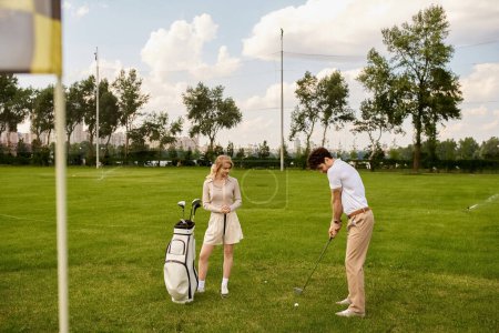A young man and woman in stylish attire play golf on a lush green field, enjoying a leisurely day together at the golf club.