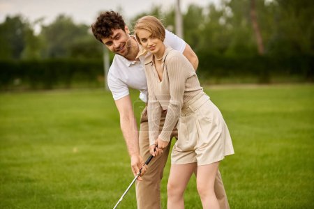 Un hombre joven y una mujer en traje elegante jugando golf en un campo verde exuberante en un club de lujo, que encarna un estilo de vida de clase alta.