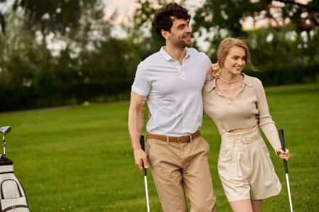 A young couple, elegantly dressed, walk on a golf course, enjoying each others company amidst lush green surroundings.