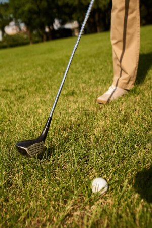 Téléchargez les photos : A man in elegant clothing prepares to tee off on a green field at a golf club, embodying old money style and upper class lifestyle. - en image libre de droit