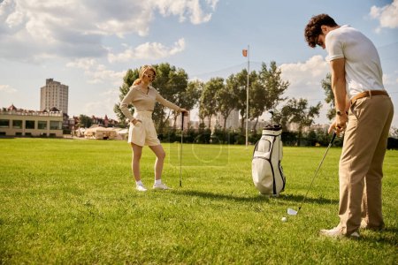 A stylish man and woman enjoy a game of golf on a beautiful green course, surrounded by nature and fresh air.