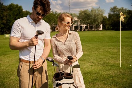 Photo for A young couple, elegantly dressed, stands together on a picturesque golf course, embodying a classic, upper-class lifestyle. - Royalty Free Image