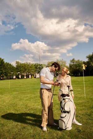 A young couple, dressed in elegant attire, stands on a lush green golf course enjoying a moment together.