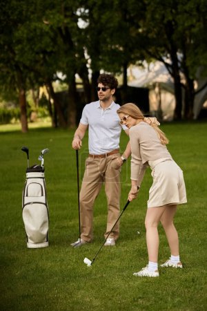 Ein junger Mann und eine junge Frau in eleganter Kleidung spielen Golf auf einer grünen Wiese in einem Park und verkörpern einen klassischen Lebensstil der Oberschicht.