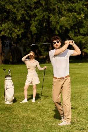 A young couple dressed in elegant attire playing golf on a lush green field in a park, enjoying a leisurely day outdoors.