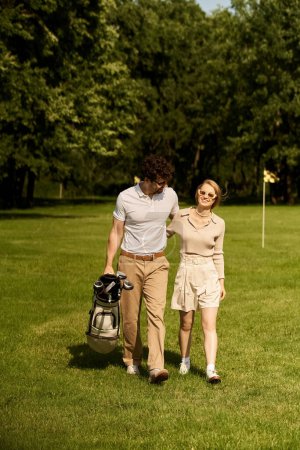 A stylish couple dressed in elegant attire leisurely walking across a manicured golf course.