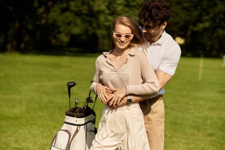 Ein junges Paar in eleganter Kleidung umarmt sich liebevoll auf einem üppig grünen Golfplatz, umgeben von Luxus und altem Geld-Charme.