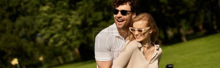 Foto de Un hombre y una mujer elegantemente vestidos abrazándose en un parque, disfrutando de una actividad al aire libre sin prisas juntos. - Imagen libre de derechos