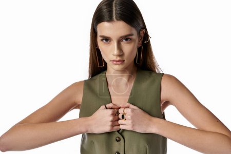 A chic woman with dark hair wears a green shirt, gracefully joining her hands together.