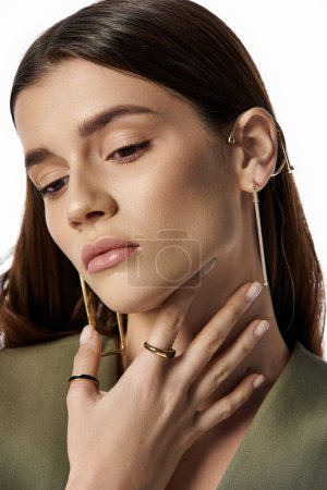 A fashionable woman with long dark hair exudes style and grace while wearing a pair of stunning gold hoop earrings on a gray backdrop.