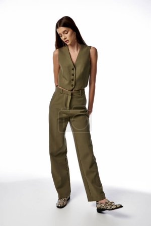 Photo for A fashionable woman with long dark hair poses in a stylish green jumpsuit and leopard print shoes on a gray backdrop. - Royalty Free Image