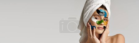 Téléchargez les photos : Une jeune femme avec des bandeaux oculaires et une serviette sur la tête, rayonnant de confiance et de beauté tout en se livrant à sa routine d'autosoin. - en image libre de droit