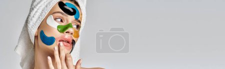 Photo for A beautiful young woman with a towel wrapped around her head, with eye patches. - Royalty Free Image