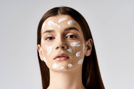 A beautiful young woman elegantly displaying a generous amount of cream on her face, showcasing a luxurious skincare routine.