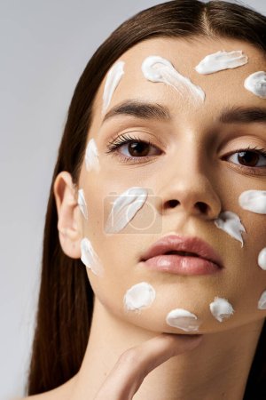 Eine junge Frau schmückt ihr Gesicht mit einer luxuriösen Menge weißer Creme, die einen ruhigen und ätherischen Glanz ausstrahlt.