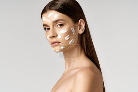 Téléchargez les photos : Une jeune femme posant avec une épaisse couche de crème sur son visage, créant une image fantaisiste et surréaliste. - en image libre de droit