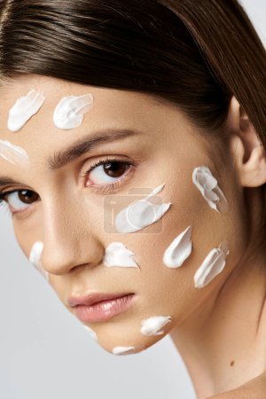 Une belle jeune femme avec une généreuse quantité de crème sur le visage, se livrant à une routine de soins de la peau.