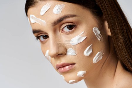 A young woman with a generous amount of cream on her face is glowing and pampering herself.