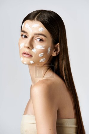 A serene and mysterious young woman adorned with a white cream on her face, exuding an aura of elegance and glamour.