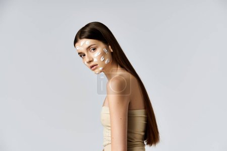 Foto de Una joven mostrando un aspecto impresionante con una intrincada crema blanca en su cara, haciendo hincapié en sus rasgos elegantemente. - Imagen libre de derechos