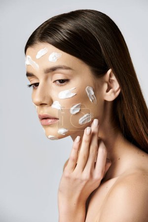 A beautiful young woman wearing a white cream on her face, exuding mystery and intrigue.