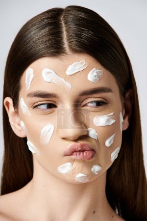 Una hermosa joven con una gruesa capa de crema blanca en la cara, creando un aspecto llamativo y etéreo.