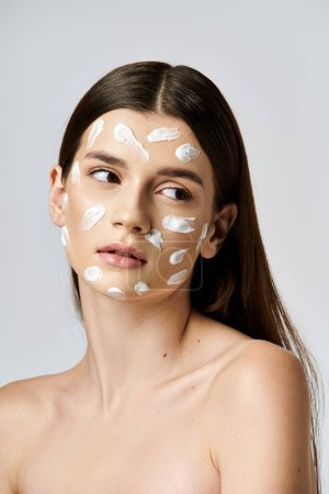 A stunning young woman wearing a white cream on her face, exuding mystery and elegance.